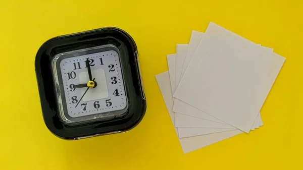 Top view of white sticky note and alarm clock with yellow color background. — Stock Photo, Image