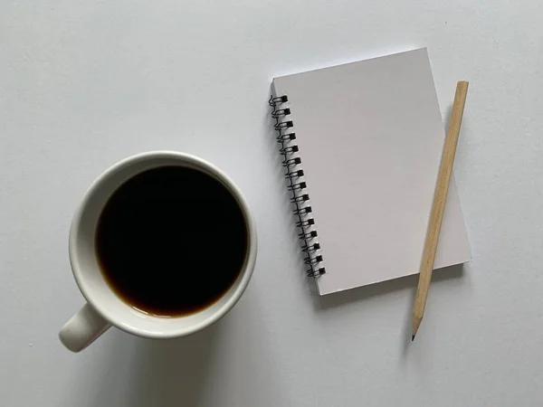 Vista dall'alto di blocco note bianco, penna e caffè con sfondo bianco. — Foto Stock