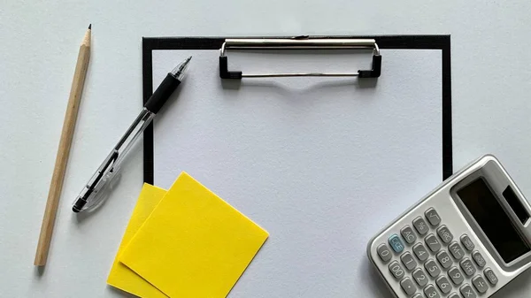 Vista dall'alto di carta bianca bianca circondata da penna, calcolatrice e note adesive. — Foto Stock