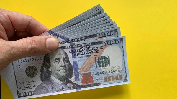 Banconota USA modello mano con sfondo giallo. — Foto Stock