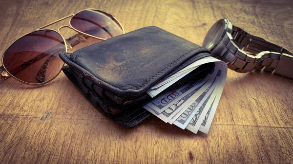 İçinde banknotlar olan eski bir cüzdanın düz görüntüsü. Güneş gözlüğü ve saat arkaplanı. — Stok fotoğraf