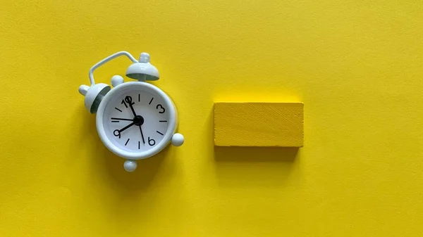 Väckarklocka på gul bakgrund med liten trä. Kopiera rymdkoncept — Stockfoto