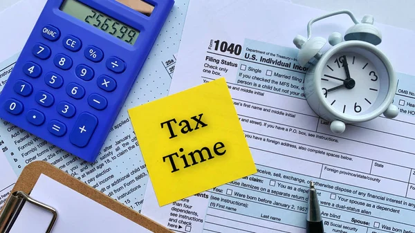 黄色のノートパッド上のテキストのトップビュー-税時間。税務フォーム、計算機、目覚まし時計とペンの背景と. — ストック写真