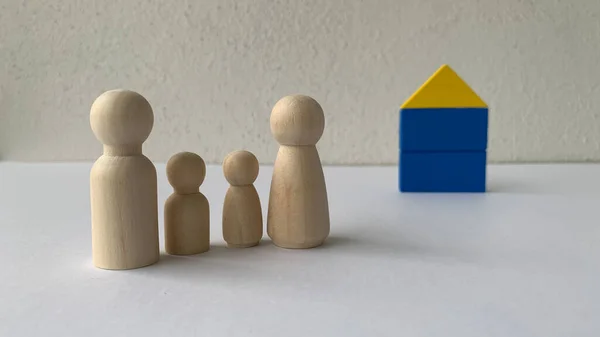 Wooden doll family stands in front of house model. Family concept — Stock Photo, Image