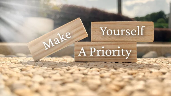 Make yourself a priority text on wooden blocks with bright sun and park background. — Stock Photo, Image