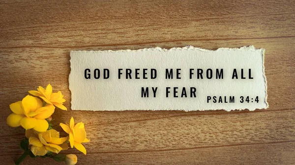 Κορυφαία άποψη του στίχου της Βίβλου Ο Θεός με ελευθέρωσε από όλους τους φόβους μου. Κίτρινο λουλούδι και ξύλινο φόντο. — Φωτογραφία Αρχείου