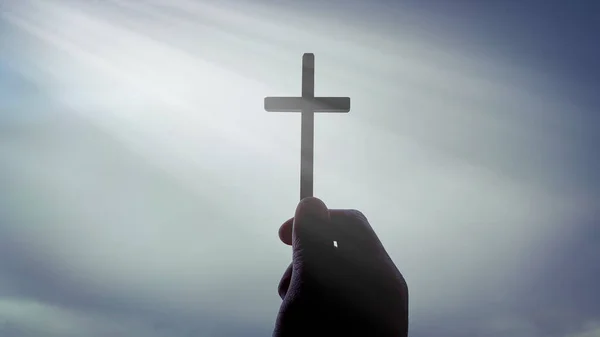 Hand die het Heilig Kruis vasthoudt met fel stralend licht vanuit de lucht. — Stockfoto