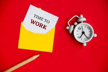 Kalem ve çalar saatle birlikte bir zarfın içinde not defteri üzerinde çalışma zamanı. Ofis saati kavramı