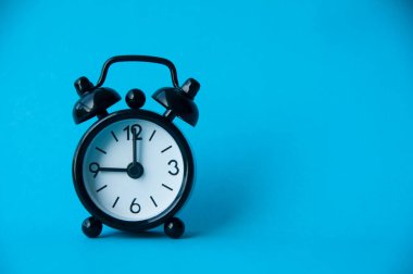 Açık mavi arkaplanda siyah alarm saati izole edildi. Saat 9 'a ayarlandı. Boşluğu kopyala.