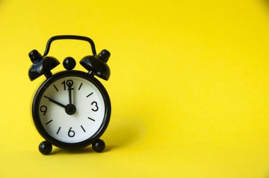 Sarı arka planda siyah alarm saati var. Saat 10 'a ayarlandı. Boşluğu kopyala.