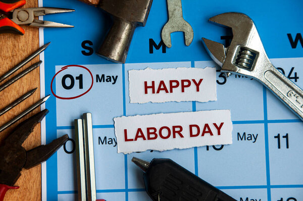 Top view of Happy Labor Day text on torn paper with calendar and working tools background. Copy space and labor day concept.