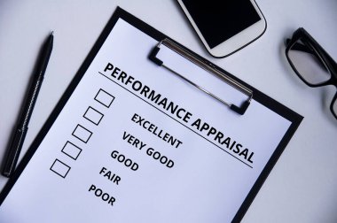 Performans Değerlendirme listesinin en üst görünümü klip tahtasında kalem, gözlük ve telefon arkaplanı ile