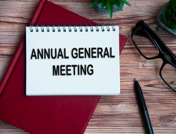 Annual general meeting text on notepad with office setting background.