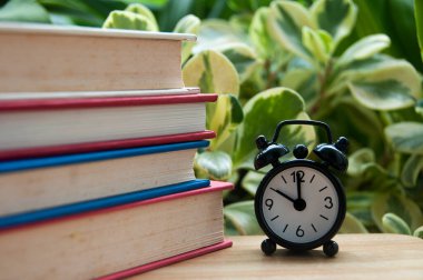 Çalar saatin saat 10 'u gösterdiği bir yığın kitap. boşluk konseptini kopyala