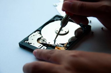 Sabit diskin içinde teknisyenlerin tornavida kullanarak tamir ettiği soyut görüntü. Veri, donanım ve bilgi teknolojisi kavramı.