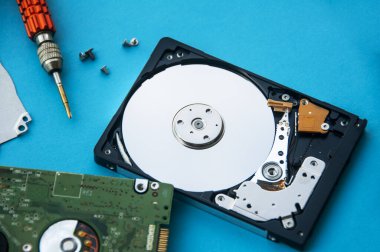 Sabit disk sürücüsünün mavi kapaklı ve vida sürücüsü arka planındaki soyut görüntüsü. Veri, donanım ve bilgi teknolojisi kavramı.