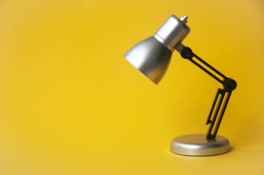 Closeup silver and black small lamp on yellow color background. Copy space
