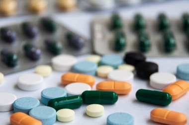 Çeşitli ilaç hapları, haplar ve beyaz arka planı bulanık olan kapsüller. Sağlık ve ilaç kavramı. Boşluğu kopyala.