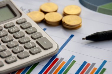 Analysis of data, chart and graphs with calculator, pen and gold coins background. Business finances and accounting concept