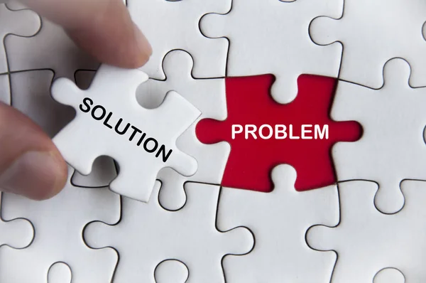 Solution and problem text on jigsaw with one hand holding a missing jigsaw pieces. Business decision concept