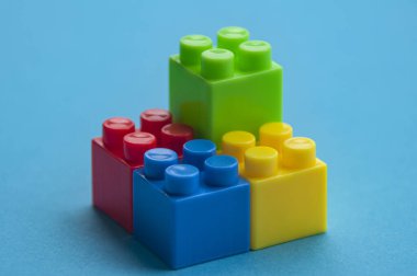 Plastic building blocks on blue background. Copy space.