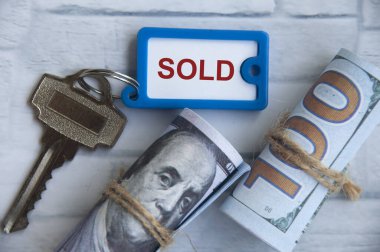 Kağıt banknot arkaplanlı anahtarlığa etiketlenmiş metin satıldı. Emlak konsepti satmak ve satın almak.