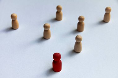 Beyaz arka planda diğer tahta bebeklere öncülük eden kırmızı tahta bebek. Liderlik ya da işe alım konsepti. Boşluğu kopyala