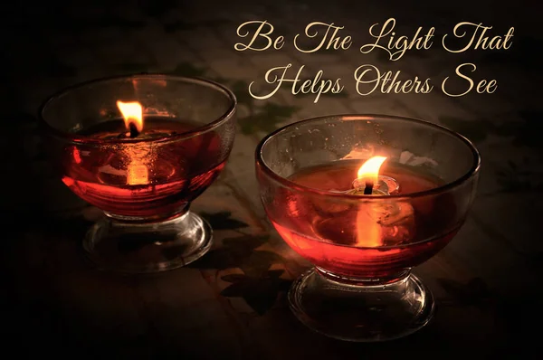 Inspirational quote - Be the light that helps others see. With candle light in wine glass.