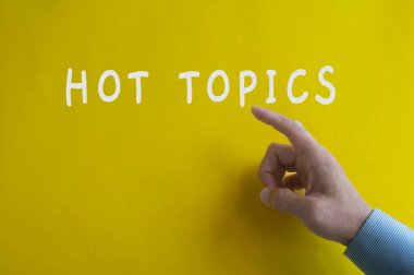 Sarı kapak arka planında el işaretli Hot Topics metni. Hot Topics konsepti