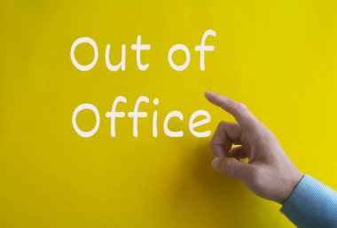 Hand pointing out of office text on yellow cover background. Out of office concept