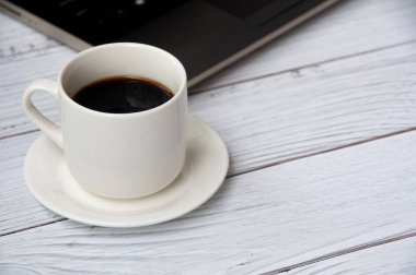Coffee cup and laptop on wooden table with customizable space for text or ideas. Copy space and office concept