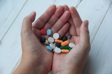 Ahşap arka planda izole edilmiş çeşitli hapları tutan kadın. Boşluk ve Tıbbi konsepti kopyala