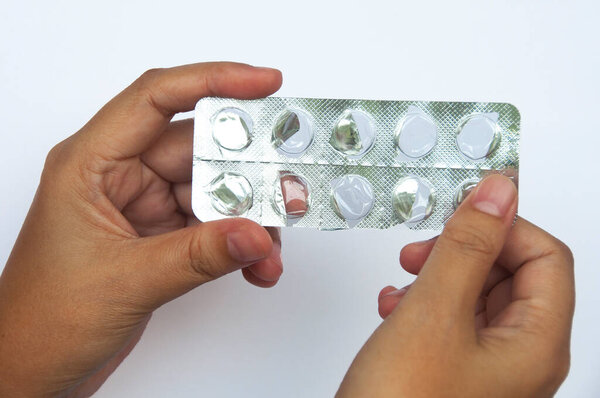 Female hand holding completed medication isolated on white background. Medical concept