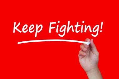 Keep fighting text on blackboard with hand holding chalk. Motivational concept
