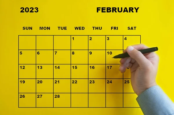 February 2023 Calendar Hand Holding Black Pen Yellow Background Appointment — Zdjęcie stockowe