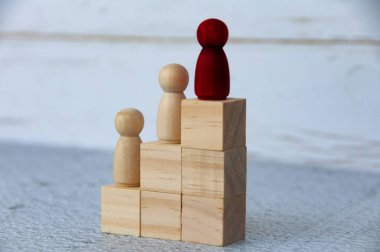 Tahta blokların tepesinde diğerlerine önderlik eden tahta kırmızı figür. Kariyer gelişimi ve liderlik kavramı.