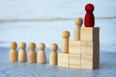 Tahta blokların tepesindeki tahta insanlar diğerlerine önderlik ediyor. Kariyer büyümesi, gelişme, liderlik ve hedef başarısı.