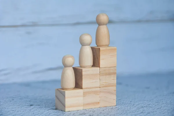Wooden figures on top of wooden blocks. Career growth and leadership concept.