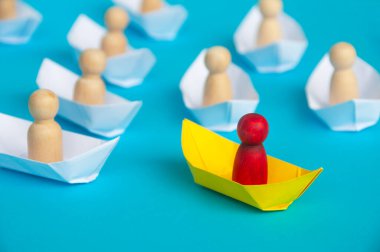 Liderlik kavramı - Kırmızı insanlar sarı kağıttan gemi origamisinde beyaz kağıt gemideki diğer insanlara önderlik ediyorlar. Boşluğu kopyala.