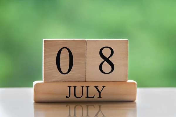 July 8 calendar date text on wooden blocks with blurred background park. Copy space and calendar concept