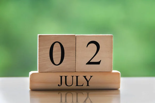 July 2 calendar date text on wooden blocks with blurred background park. Copy space and calendar concept