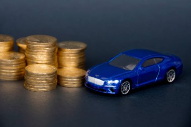 Kuala Lumpur, Malaysia - July 2022 : Miniature toy car of Bentley Continental GT with gold coins on black cover background. Copy space.