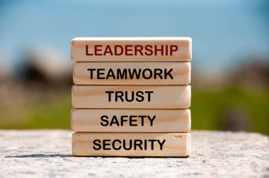 Leadership, teamwork, trust, safety and security text on wooden blocks with blurred nature background. Leadership concept