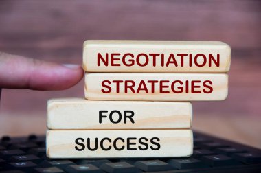 Negotiation strategies for success text on wooden blocks. With keyboard and blurred wooden background.