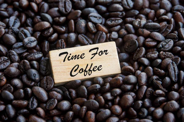 Time for coffee text on wooden blocks with coffee beans background. Food and beverage concept