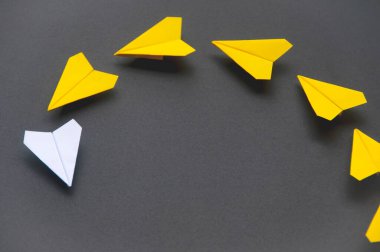 White paper plane origami leading yellow planes on dark background. Leadership skills concept.