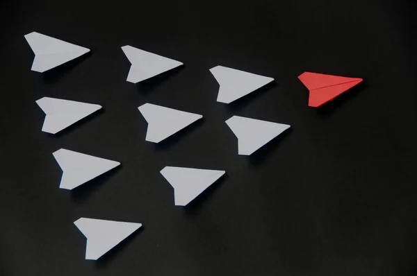 Red paper plane origami leading white planes on dark background. Leadership skills concept.
