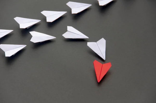 Red paper plane origami leading white planes on dark background. Leadership skills concept.