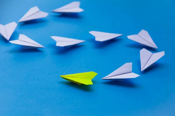 Yellow paper plane origami leading white planes on blue background. Leadership skills concept.
