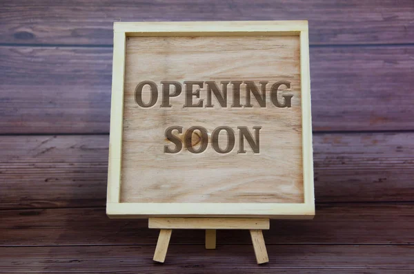 Opening soon text engraved on wooden frame. Business opening concept.